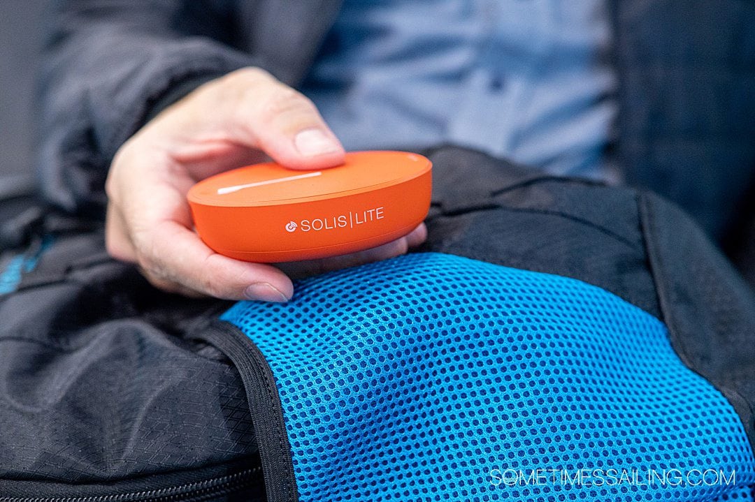 Hand holding an orange wifi Skyroam Solis hotspot.