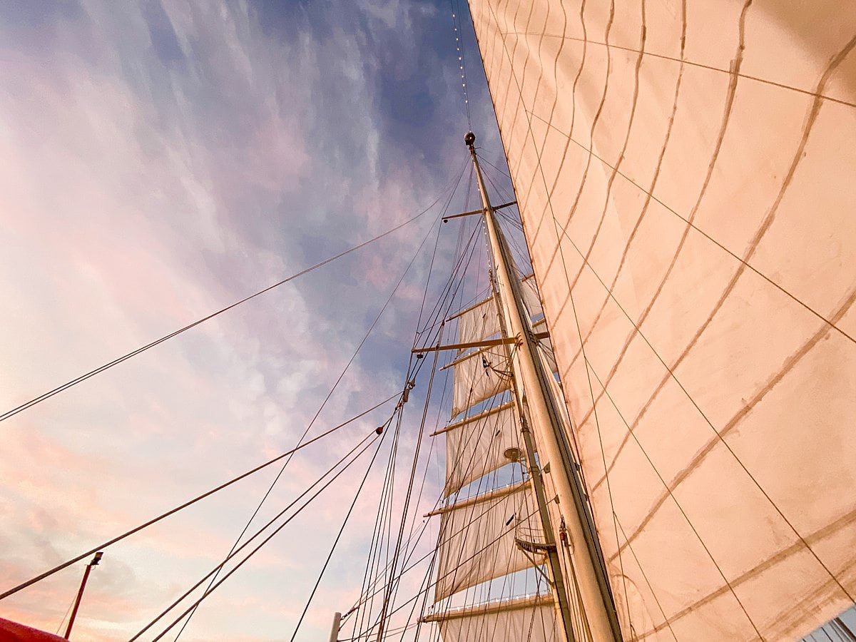 Sails of Star Clipper ship with a blue and purple sky behind it.