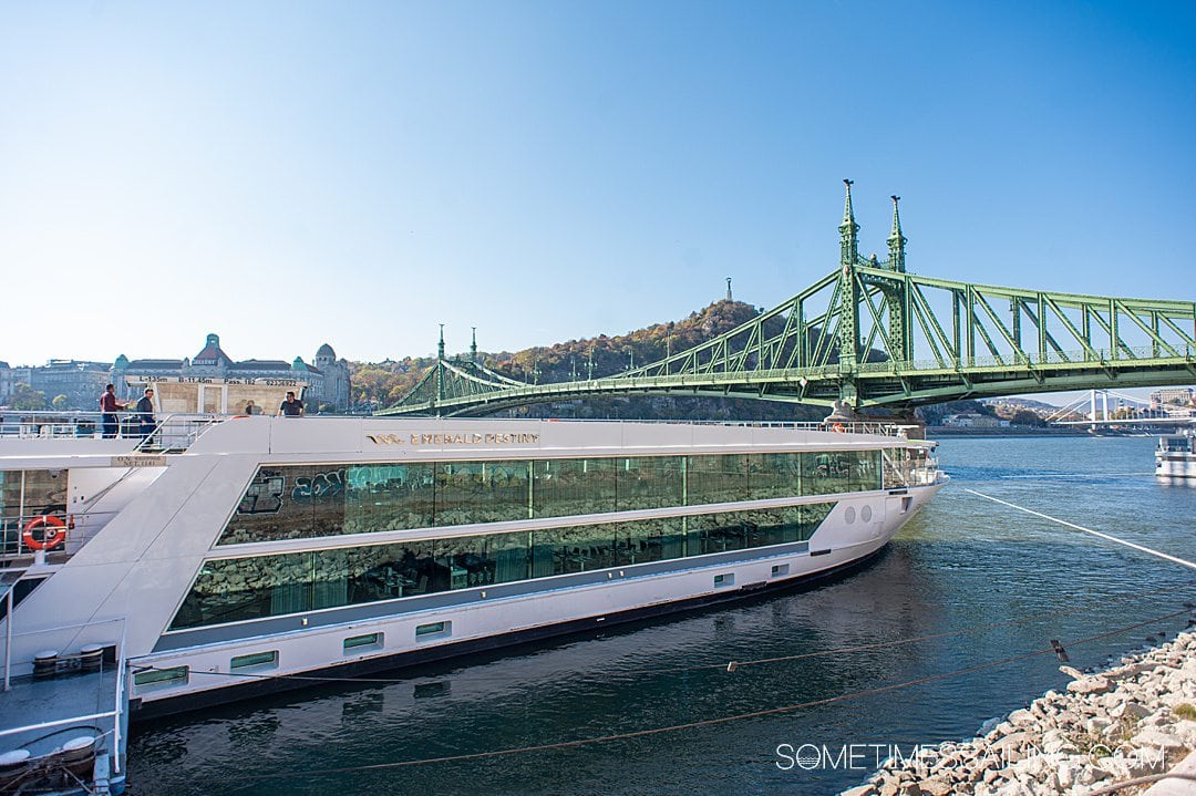 Exterior of the Emerald Destiny river cruise ship with Budapest's green bridge in the distance, on the Danube River in Europe.