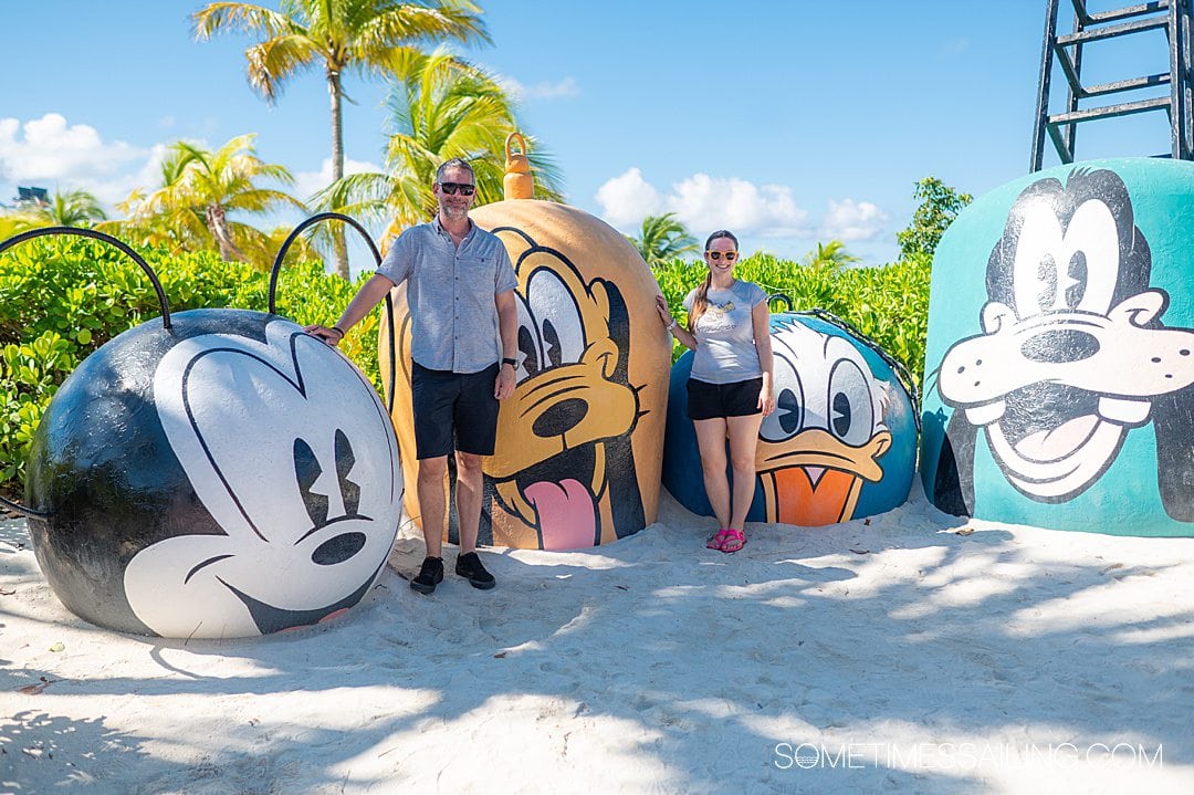 Disney-character painted anchors in the sand with lush foliage behind them on Castaway Cay, Disney's private island, for the best cruises to take this year.