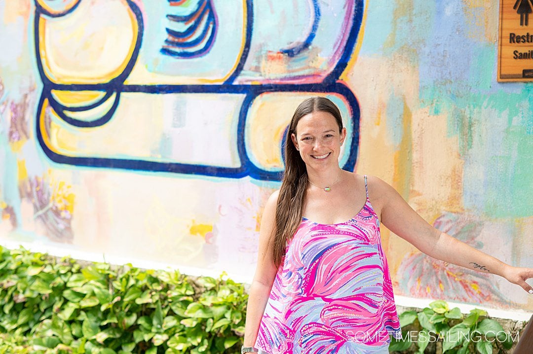 Woman in a colorful tank top with a Mayan inspired mural behind her.