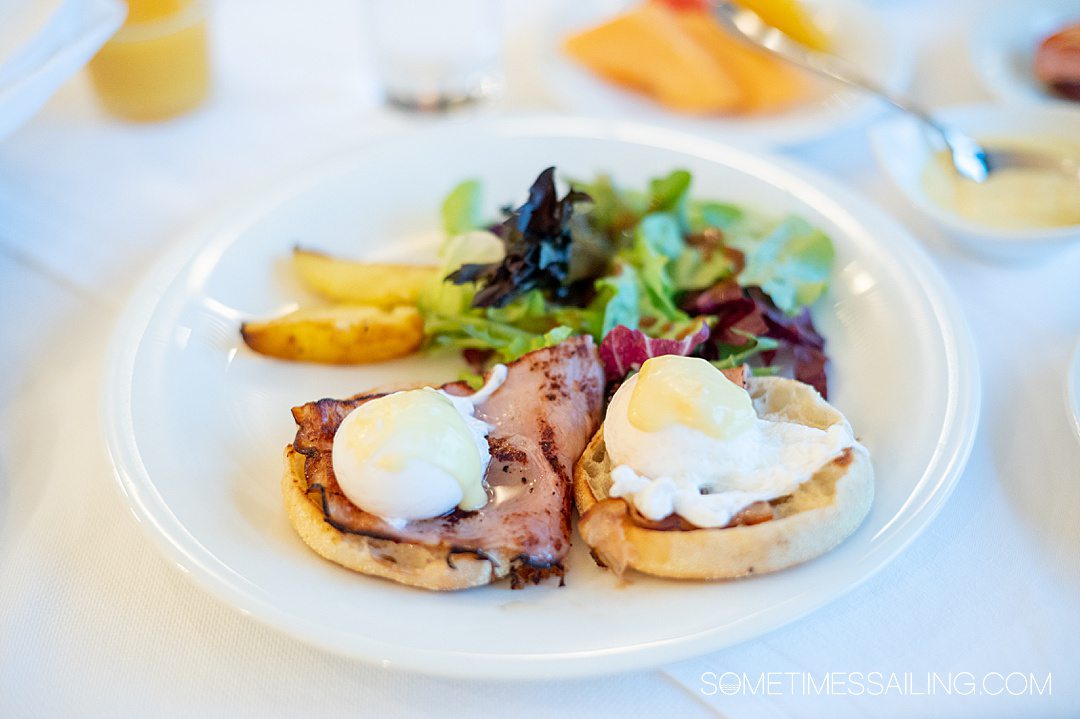 Eggs Benedict and green salad on a plate for breakfast during an AmaWaterways river cruise.