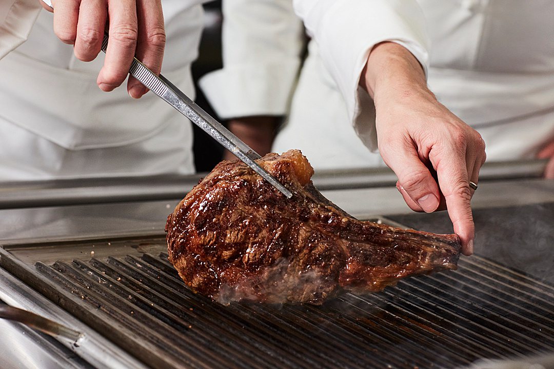 Steak with tongs holding it.