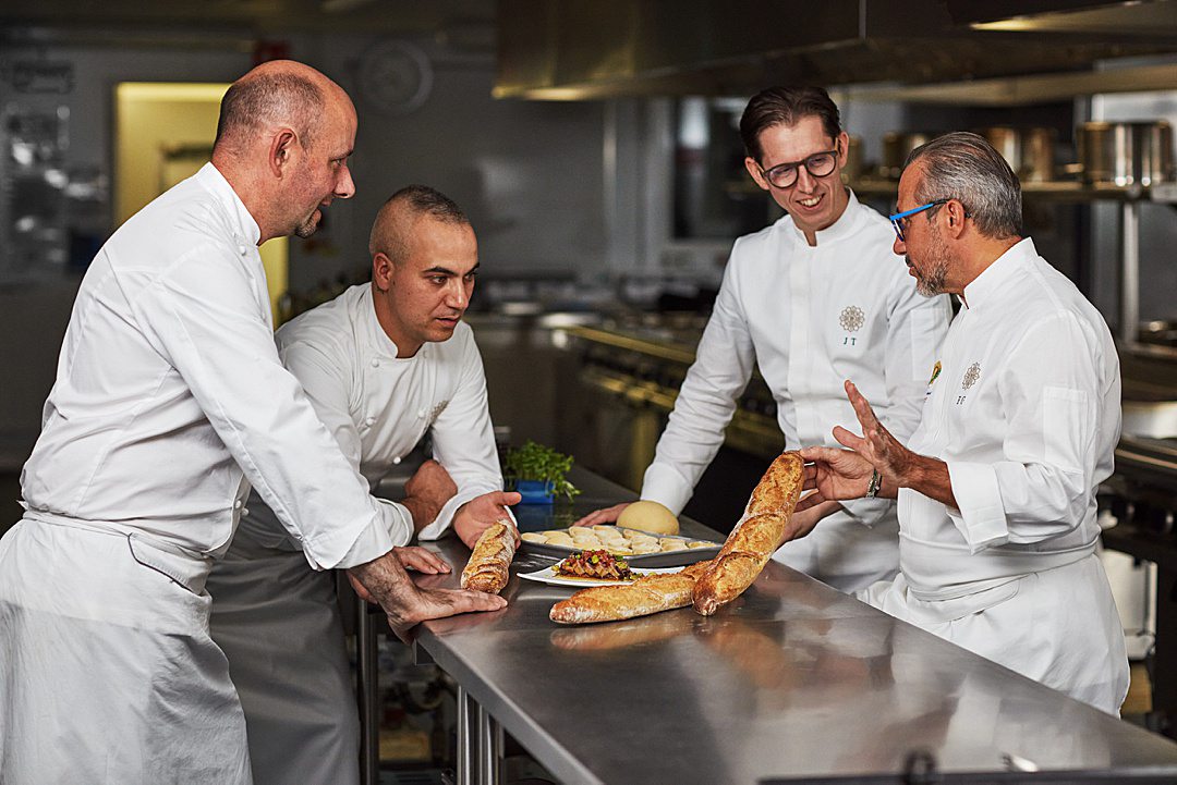 Culinary team around a kitchen table with fresh ingredients for Explora I culinary cruise menu.