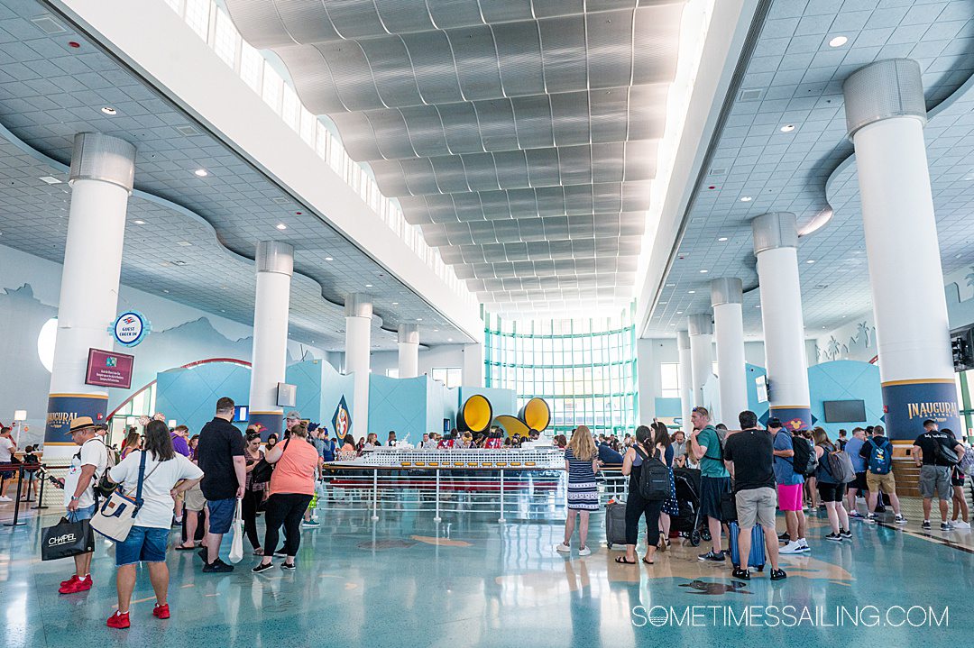Inside the Disney Cruise Line terminal, with high ceilings and a blue floor, filled with a lot of people.