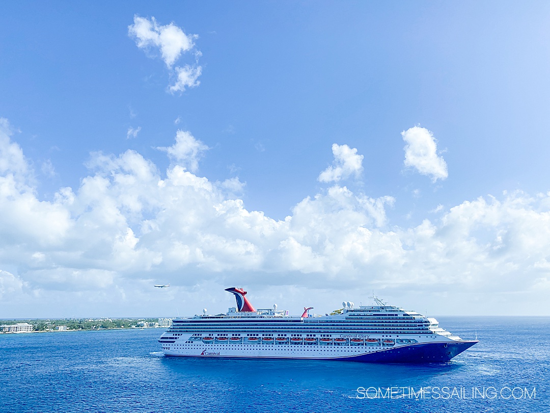 Carnival Cruise Ship in the ocean with a blue sky and white clouds and airplane overhead in the Caribbean.