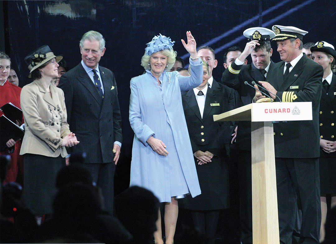 His Majesty King Charles III and The Queen Consort wave to the crowd from a platform during Cunard's Queen Victoria naming.