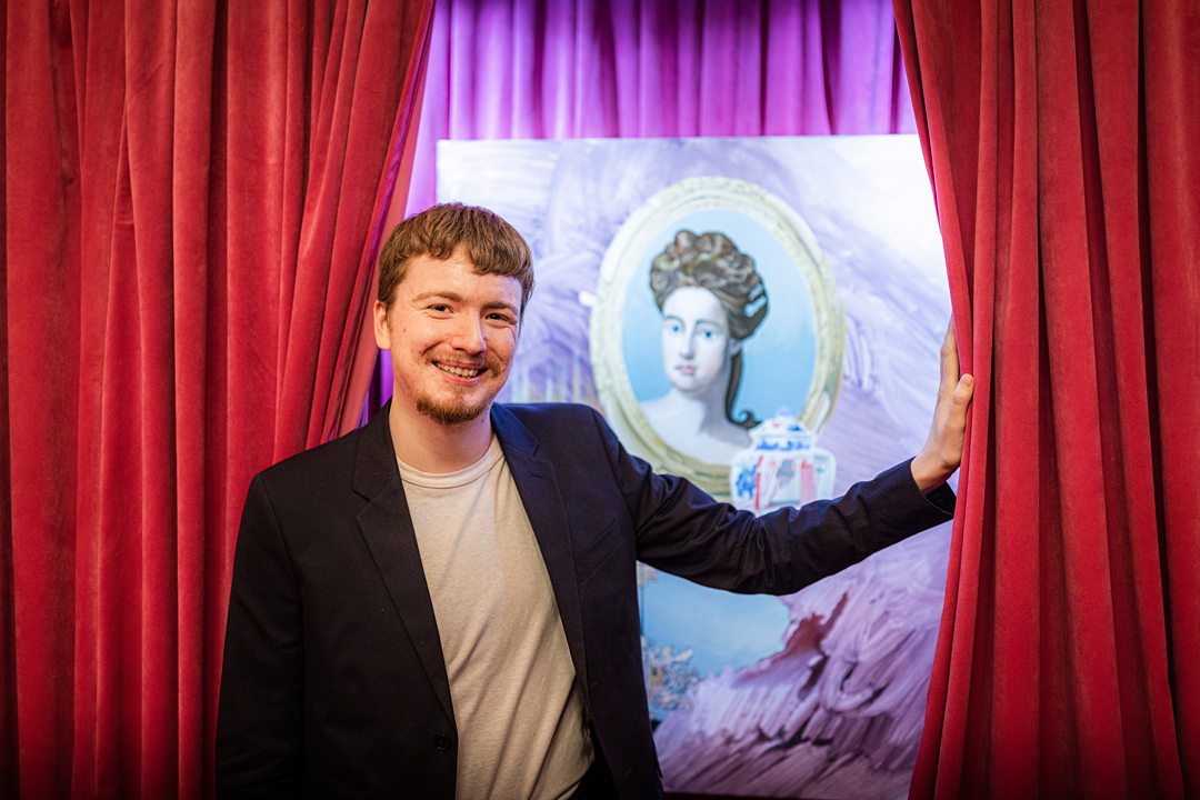 Artist Tommy Camerno reveals his Cunard commissioned portrait of Queen Anne by pushing back a red curtain. Image by Christopher Ison.