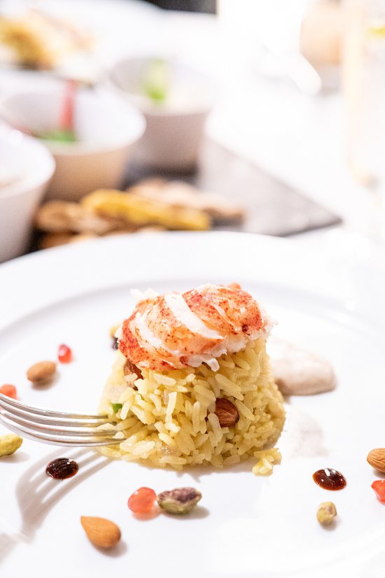 Dish of rice, almonds and pistachios with a piece of lobster tail on top