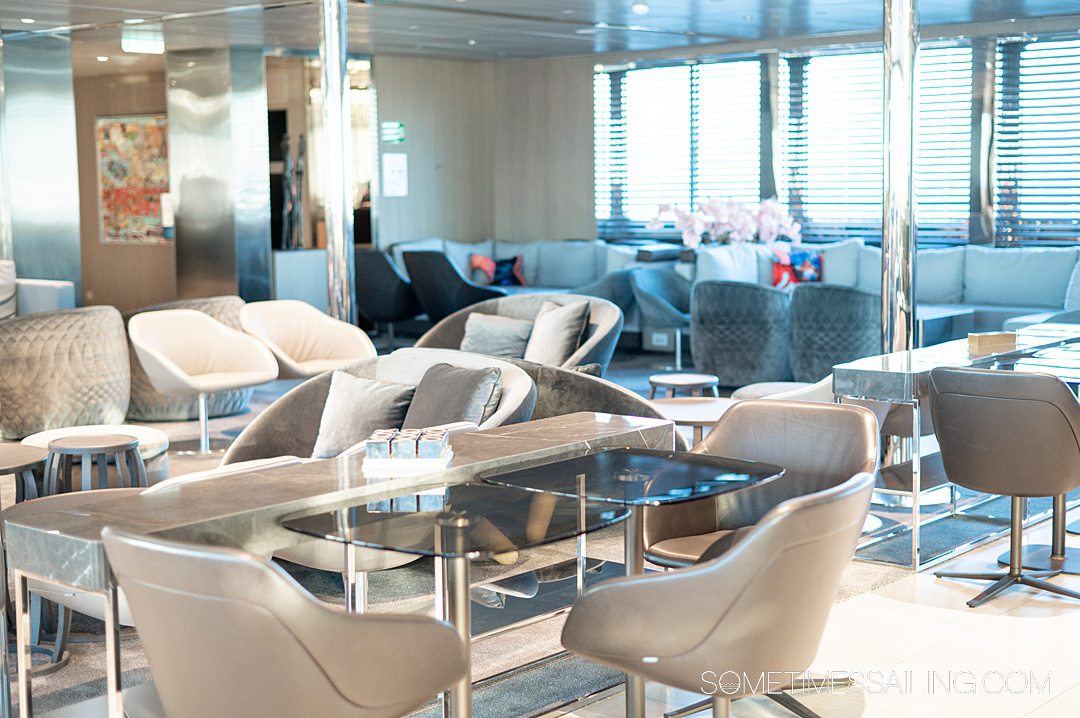 Interior lounge of Emerlad Azzurra yacht cruise ship with neutral color furniture and tables.