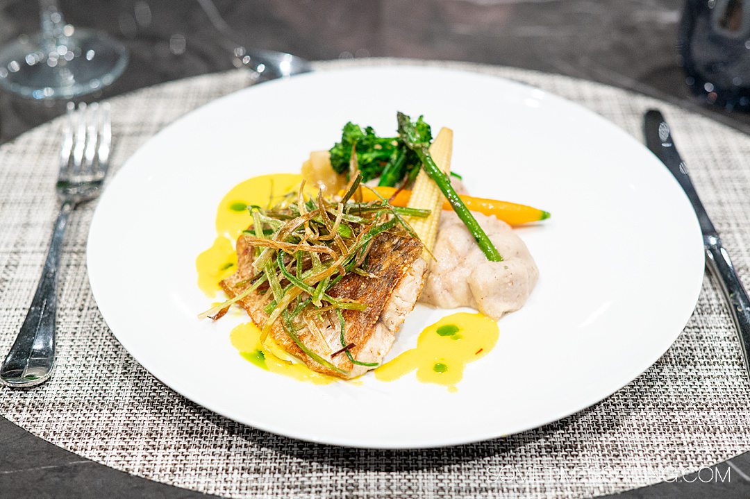 Fish dish with a yellow sauce and vegetables in La Cucina on Emerald Azzurra yacht cruise ship.