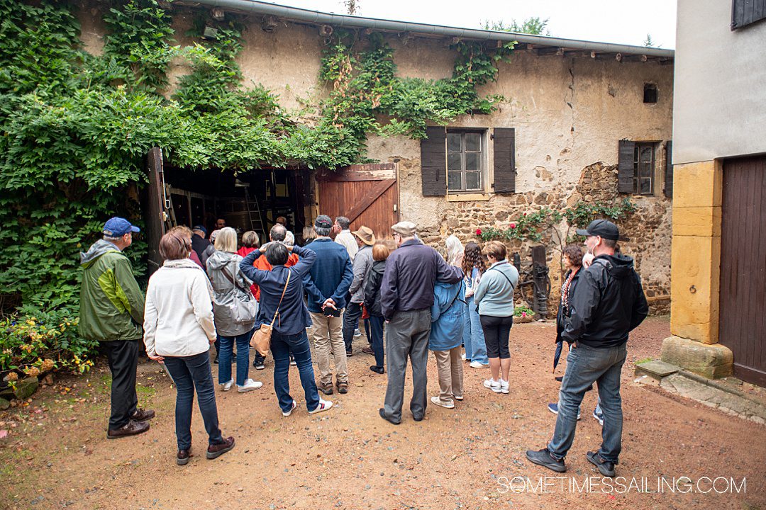 Group of people looking at an ivy-covered building at Domaine du Bois Pothier vineyard in Beaujolais, France during an excursion for an AmaWaterways cruise.