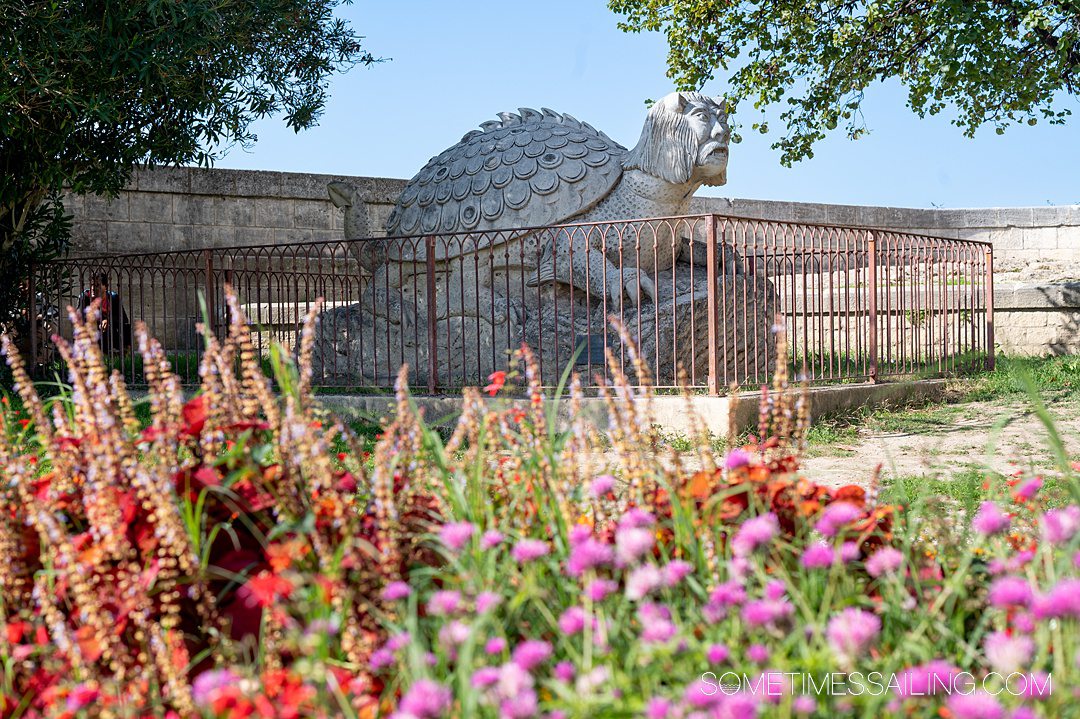 Flowers in the foreground with a mythical sculpture in the background in Tarascon, France.