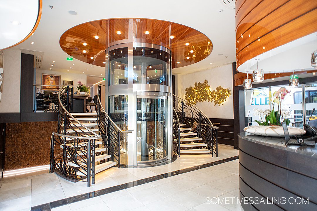 Round elevator surrounded by two wrap-around staircases spanning one floor to another on AmaKristina river cruise ship.