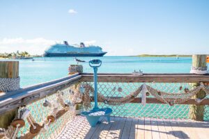 Disney Wish cruise ship in the background with a Castaway Cay deck with fish netting in the foreground in the Caribbean.