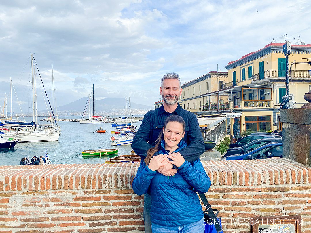 A couple on a brick bridge with the Port of Naples and Mount Vesuvius in the background.