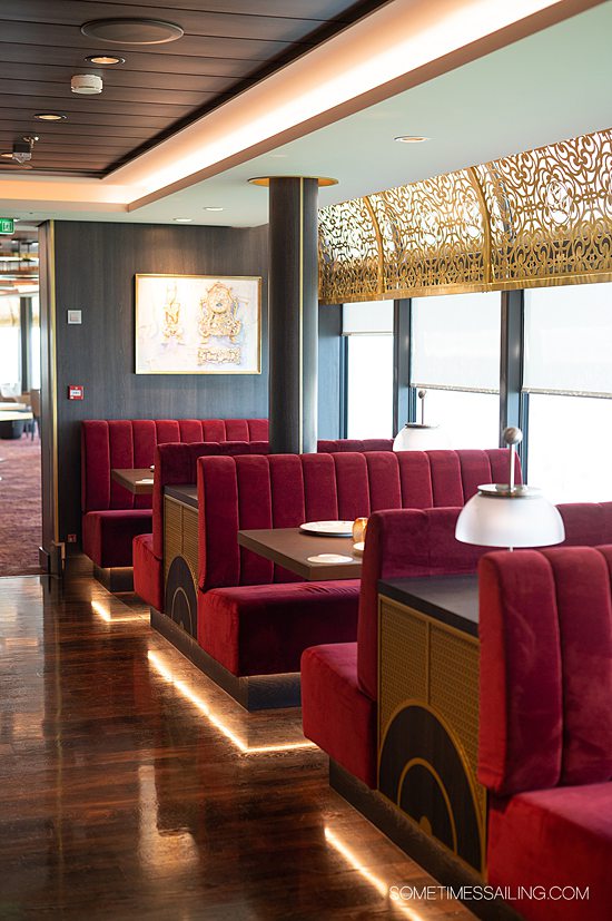 Red, gold and off-white interior of Palo restaurant on Disney Wish cruise ship, with red velvet booths.