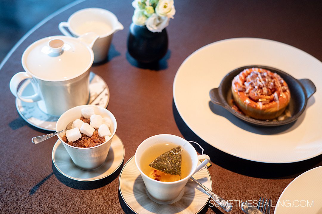 Table with tea cups and sugar on the left, and cinnamon bun on the right at Palo Italian restaurant.