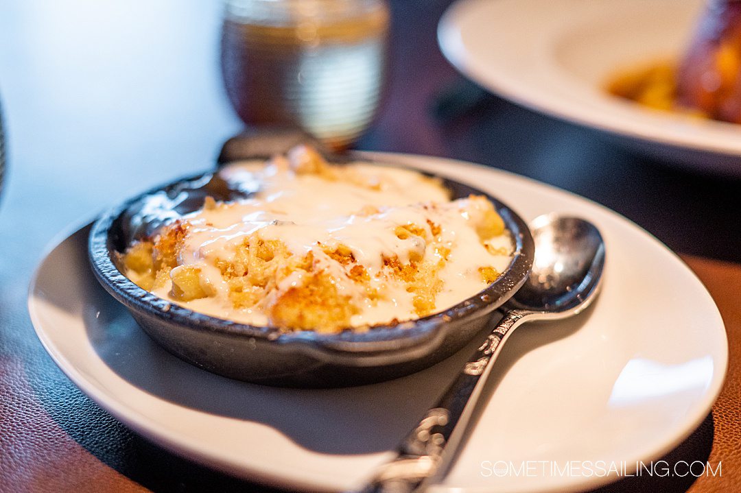 Small cast iron skillet with macaroni and cheese covered with liquid cheese and breadcrumbs.