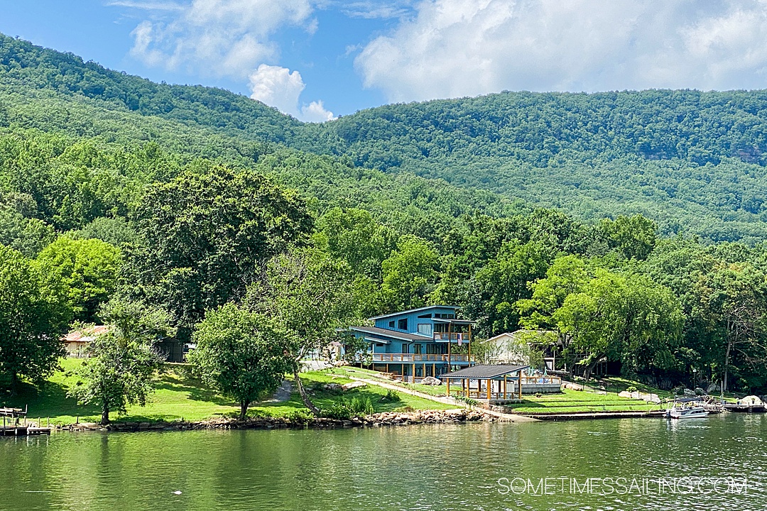 Green mountains and reflective Tennessee River with a blue house on the water during a river cruise in the USA.