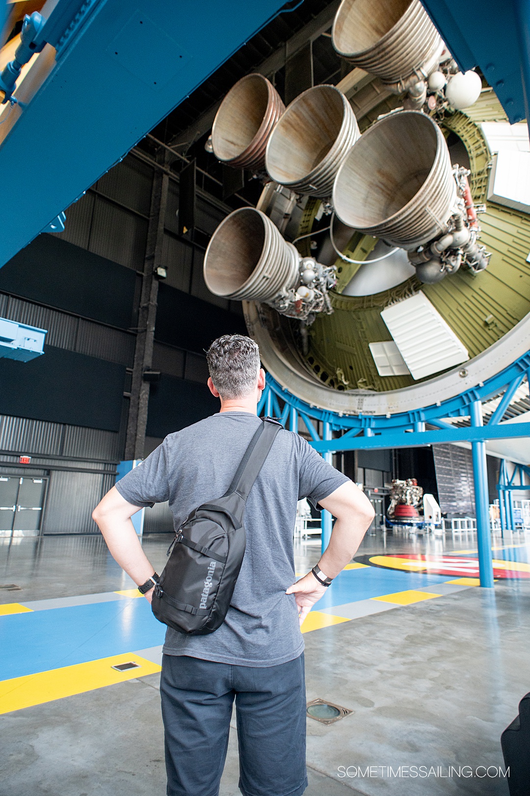 Man looking up at the engine of a Saturn rocket at NASA space center.