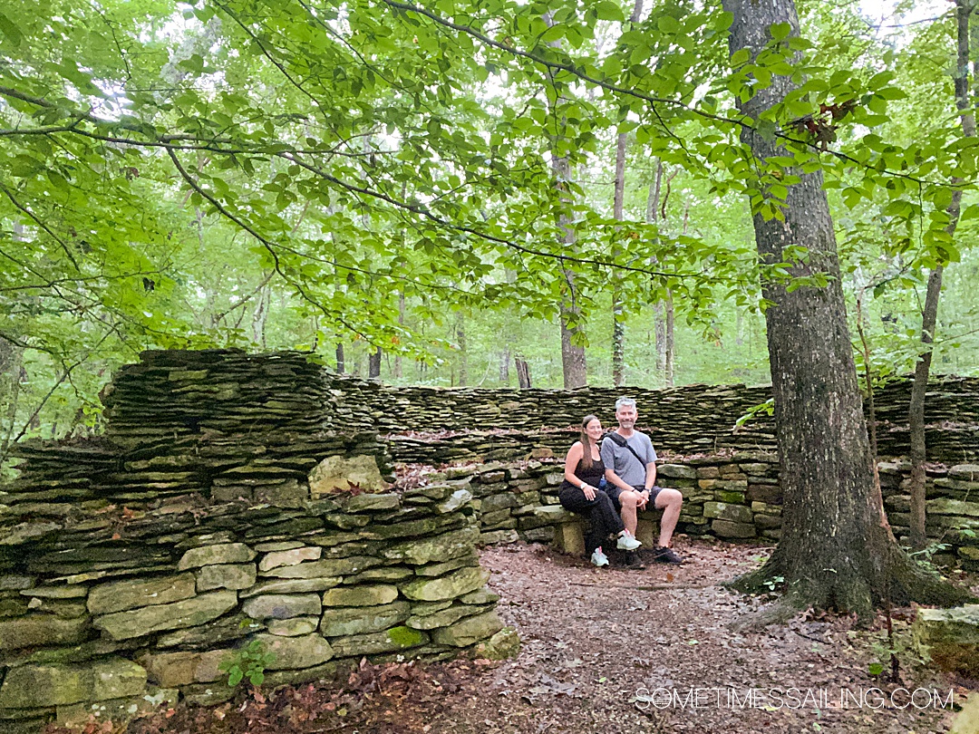 Couple by Tom's Wall, a sacred Native American site, in Alabama by green trees during a Tennessee river cruise.