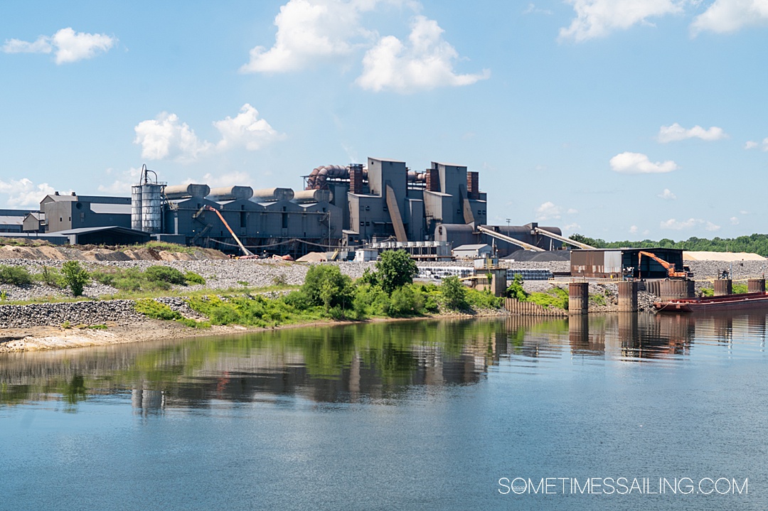 Industrial factory reflecting in the Tennessee River on a blue sky day.