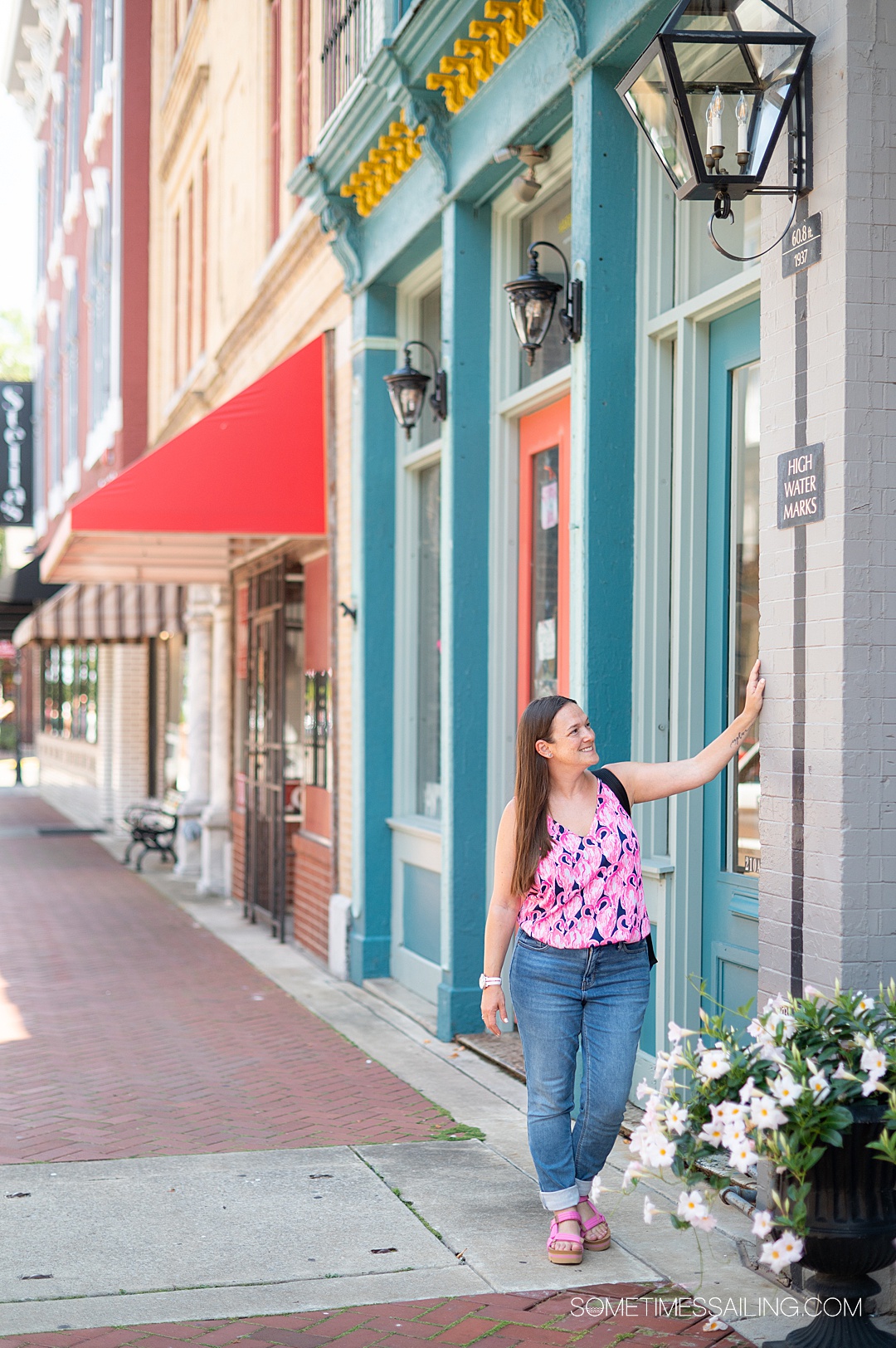 Woman looking at the water mark line on a wall in Paducah, Alabama, with a blue painted wall behind her on the main street of the town.