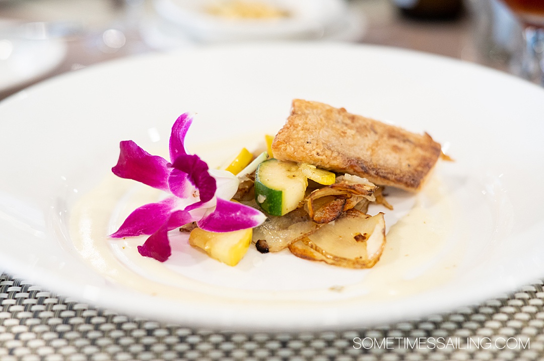 Plate of food with a purple orchard on the left on an American Cruise Lines ship.