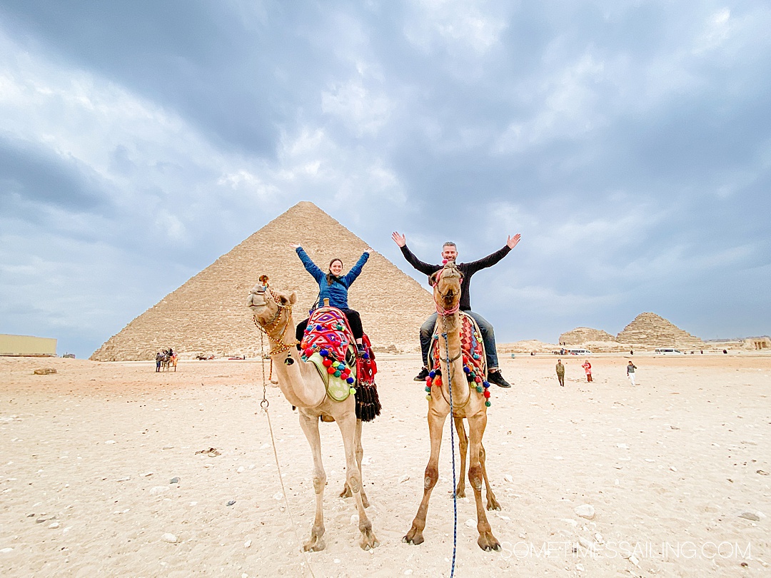 Two people on camels in front of the Pyramids of Giza in Egypt. 