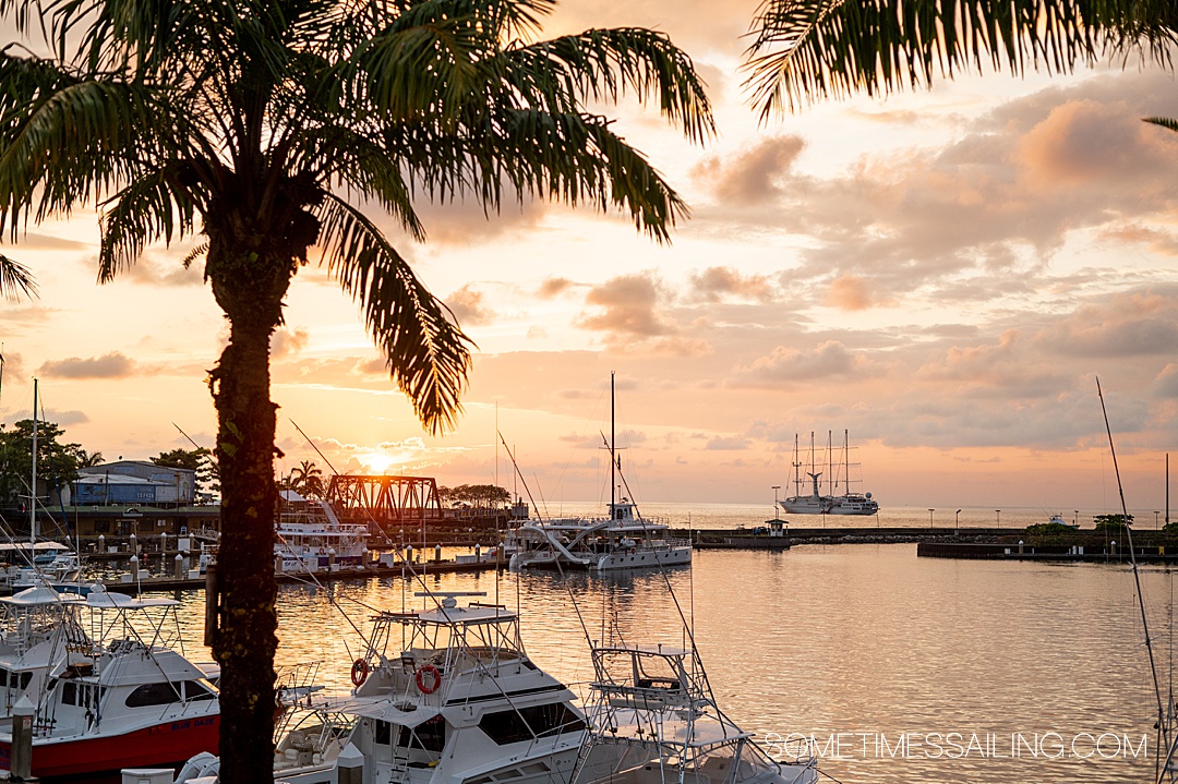 Orange sunset during a winter cruise in Costa Rica on the Pacific coast with boats in the harbor and cruise ship in the distance.