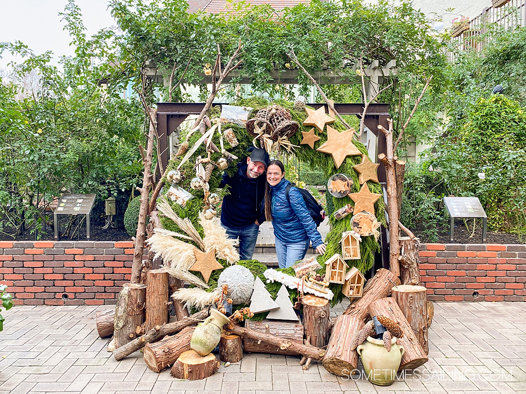 Couple looking through a huge holiday wreath for Christmas Markets in Europe.