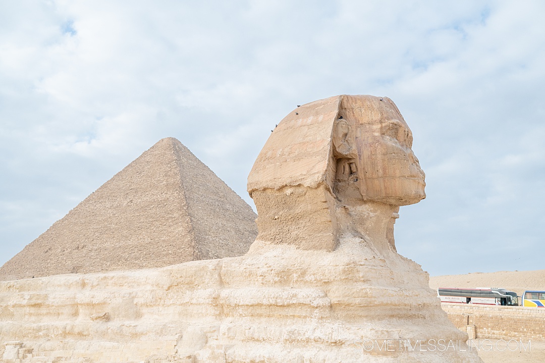 The Great Sphinx in Giza, Egypt, seen from the side with a pyramid behind it to the left.