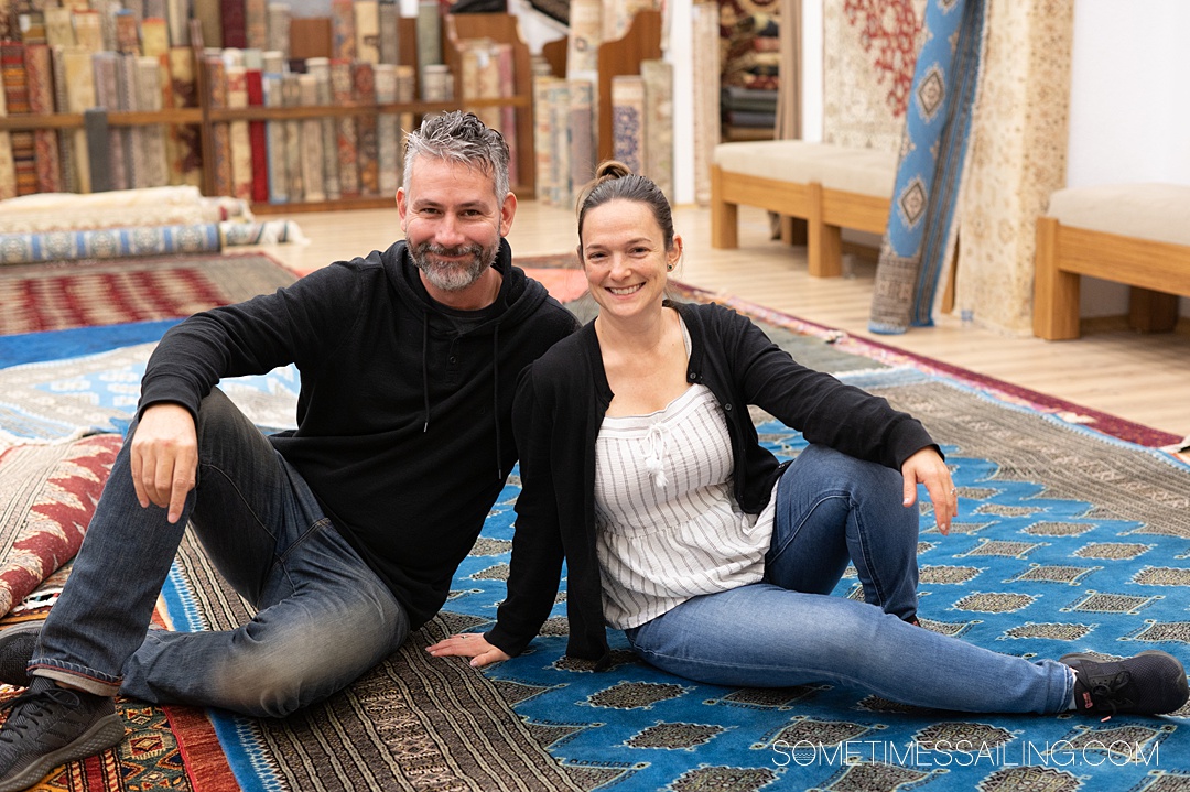 Man and a woman sitting on a blue rug at a Turkish store during a Celestyal Cruises excursion in Kusadasi.