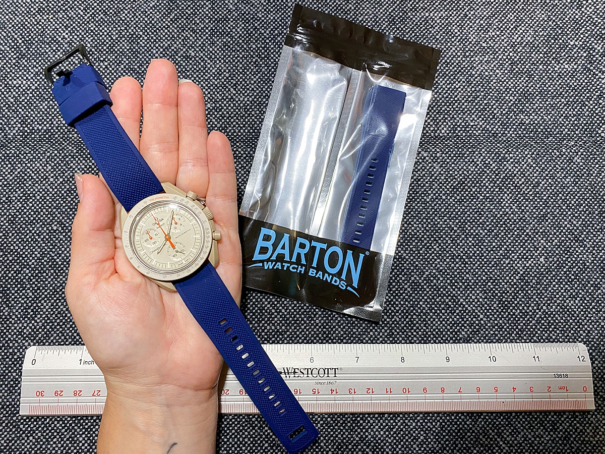 Barton watch bands with a hand holding a watch with a blue band and a ruler in the background.