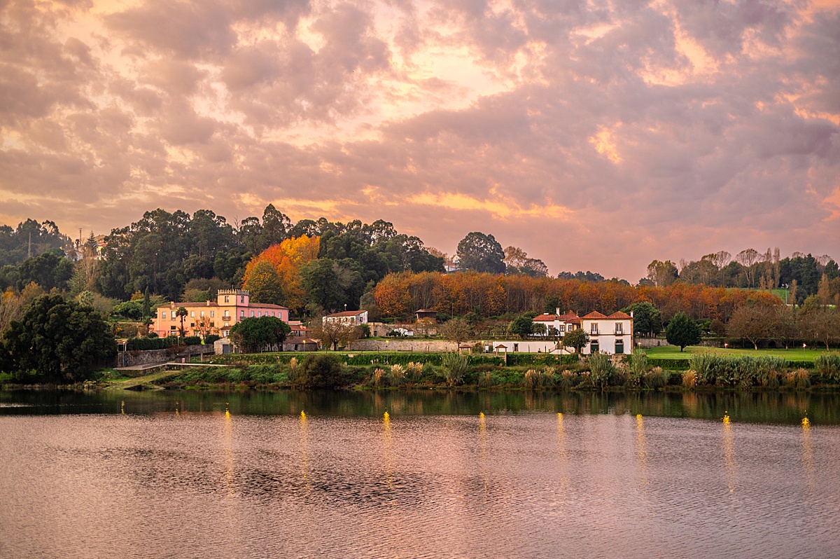 Viking's Douro River during sunrise with a purple and pink sky and castle looking building in the distance.