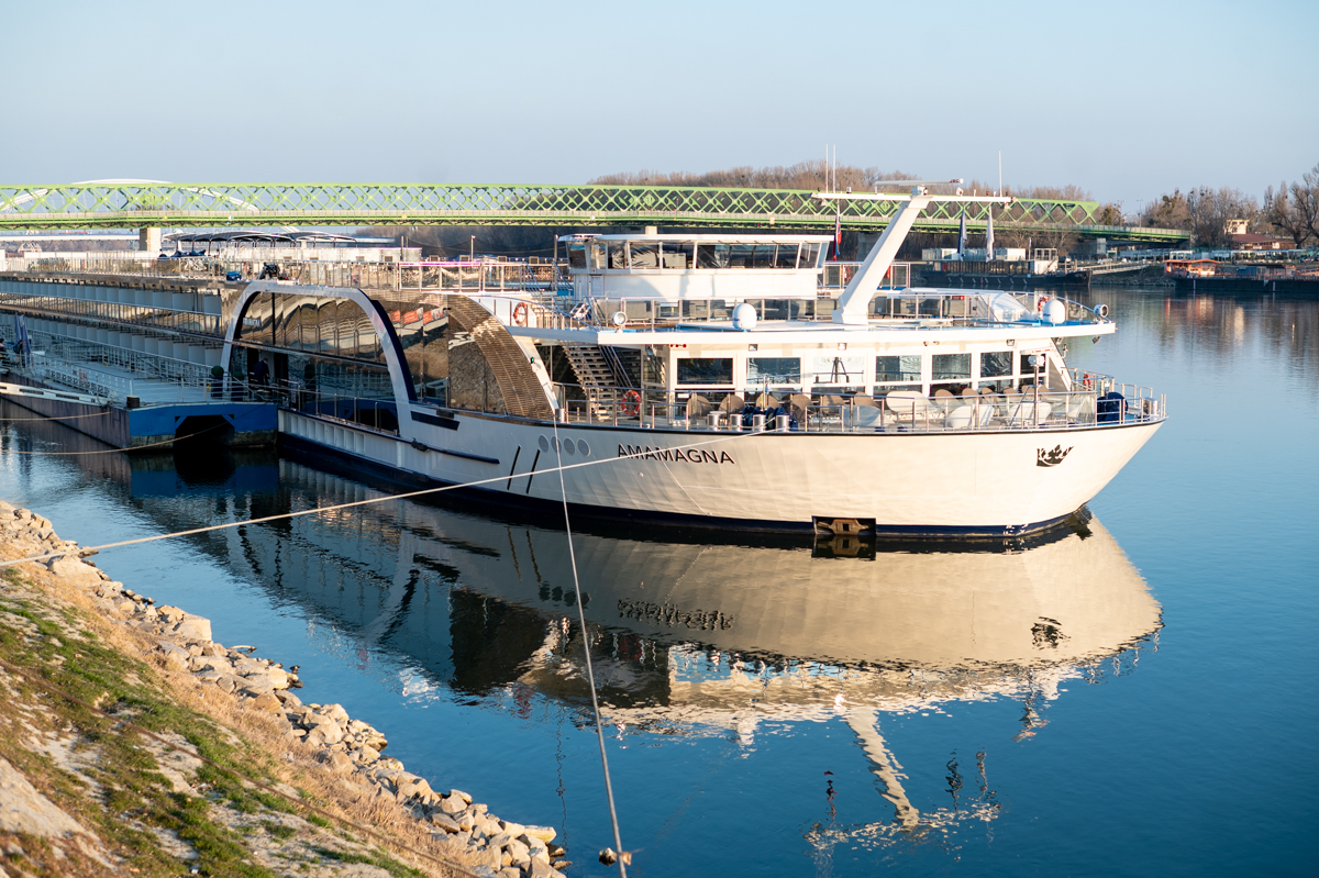 AmaMagna river cruise ship reflecting on the Danube River during a sunny day.