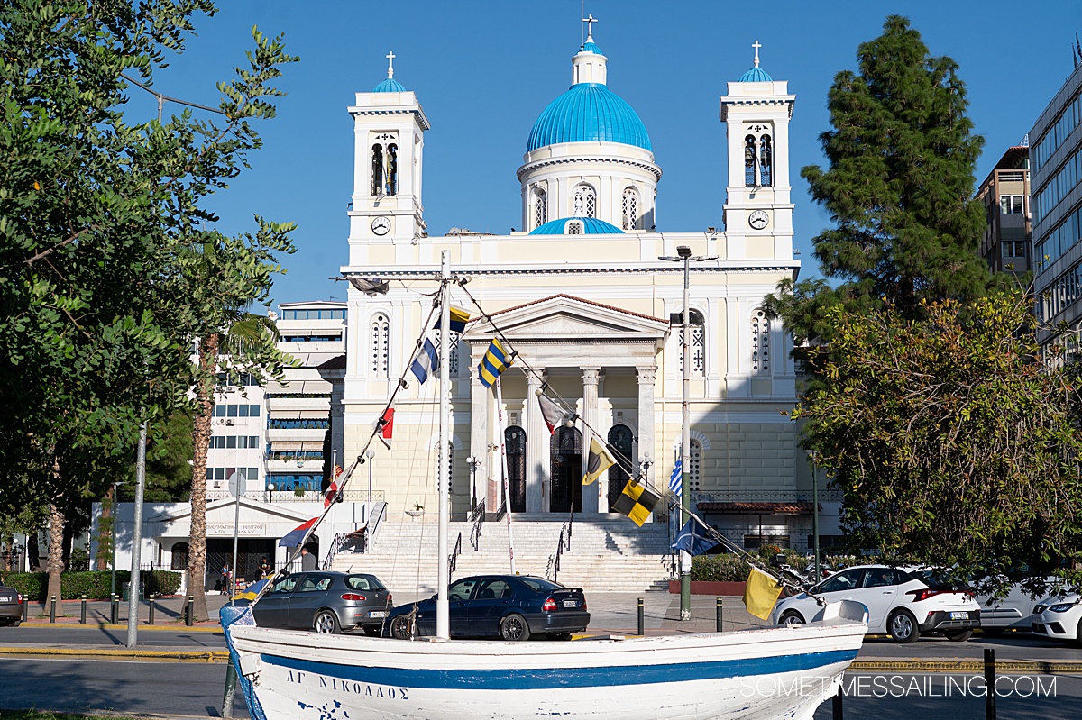 Church with a blue dome in Piraeus, Greece, with a boat in front of it.