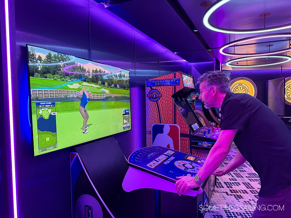 Man playing "Golden Tee" golf arcade game at an indoor club venue on Celebrity Cruises Xcel ship.