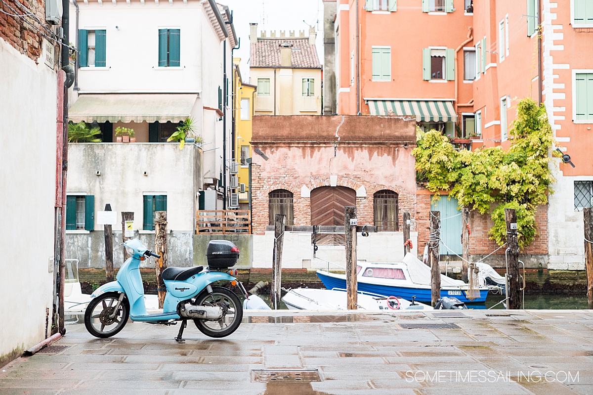 Blue Vespa along the canal in historic Chioggia, Italy.