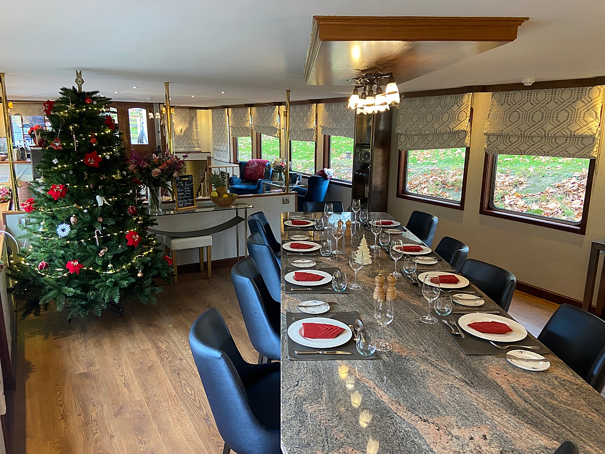 Christmas tree behind a table set for a holiday dinner on Panache barge cruise ship.