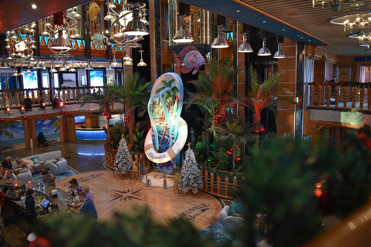 The atrium of Margaritaville at Sea and its iconic Flip Flop with Christmas decorations and trees surrounding it.