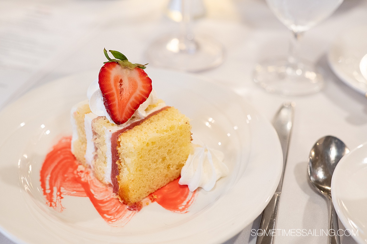 Strawberry shortcake dessert on a plate with strawberry sauce and whipped cream.