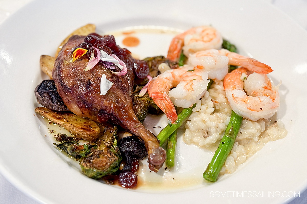 Plate with a duck leg on the left and shrimp on the right.