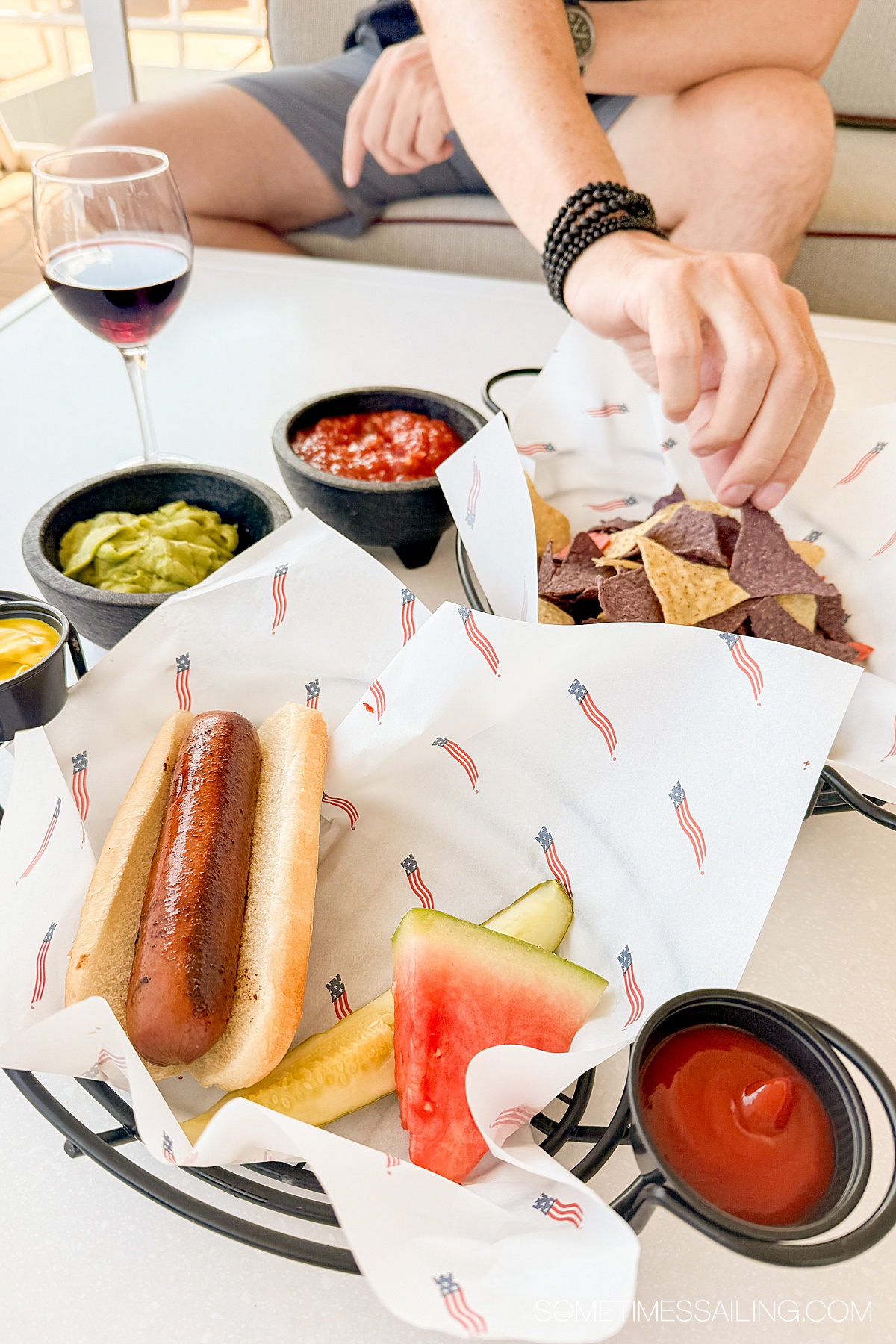 Basket with a hot dog, watermelon, and chips and dip.