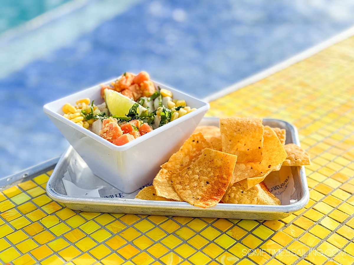 Plate with chips and a square bowl of ceviche and blue and yellow in the background.