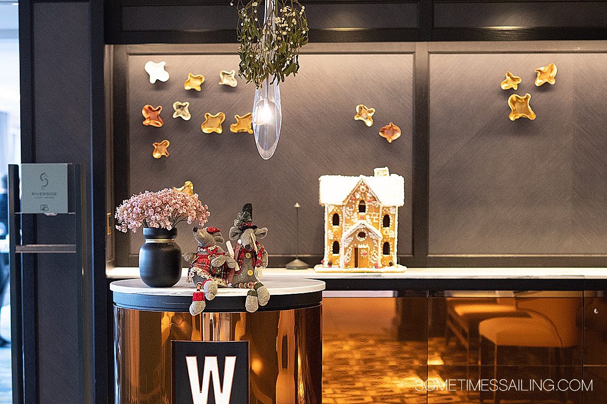 Hostess stand with Christmas mice dolls on it, a gingerbread house behind it and mistletoe hanging from the light.
