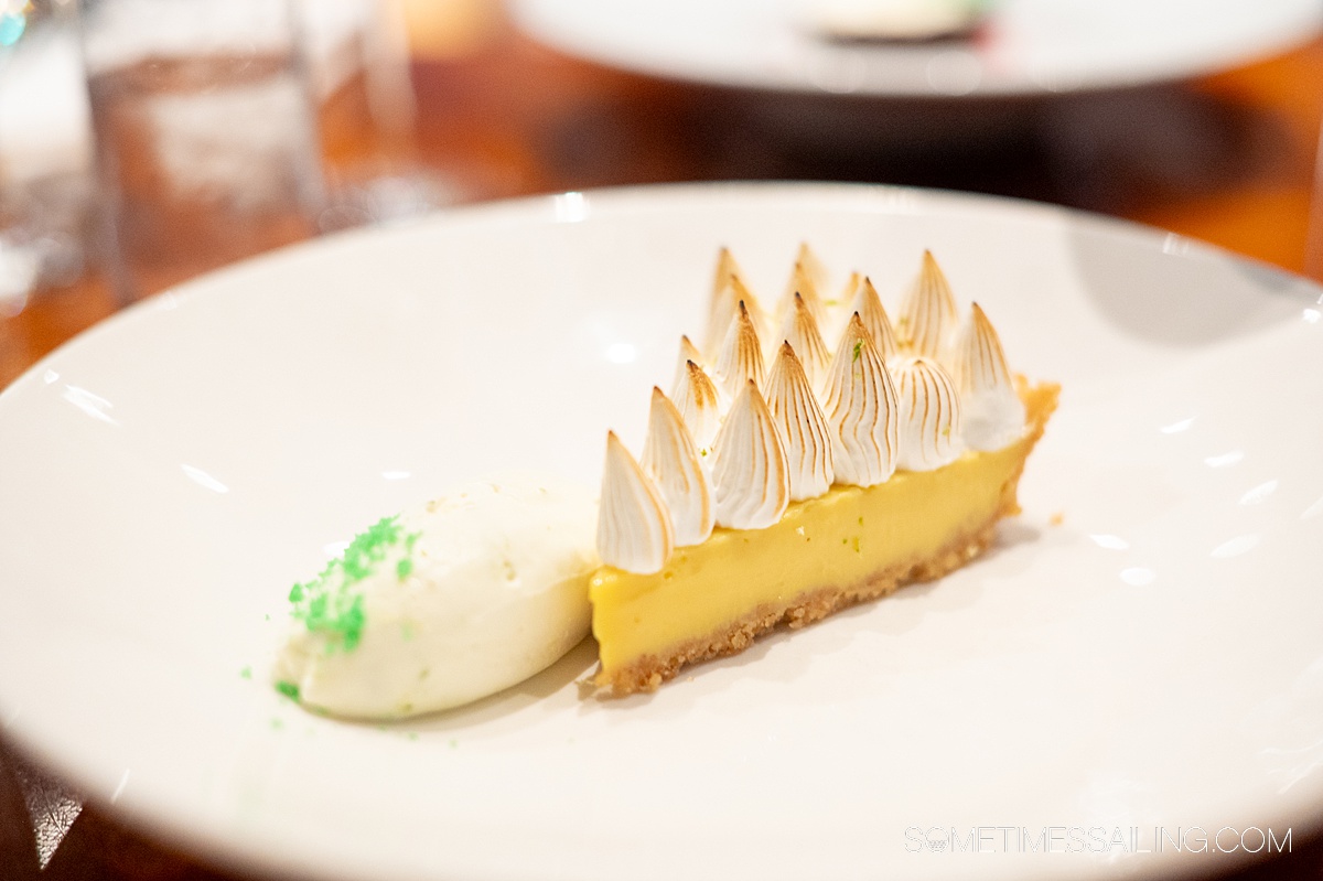 A slice of Key Lime pie topped by meringue with a dollop of cream next to it on the plate.
