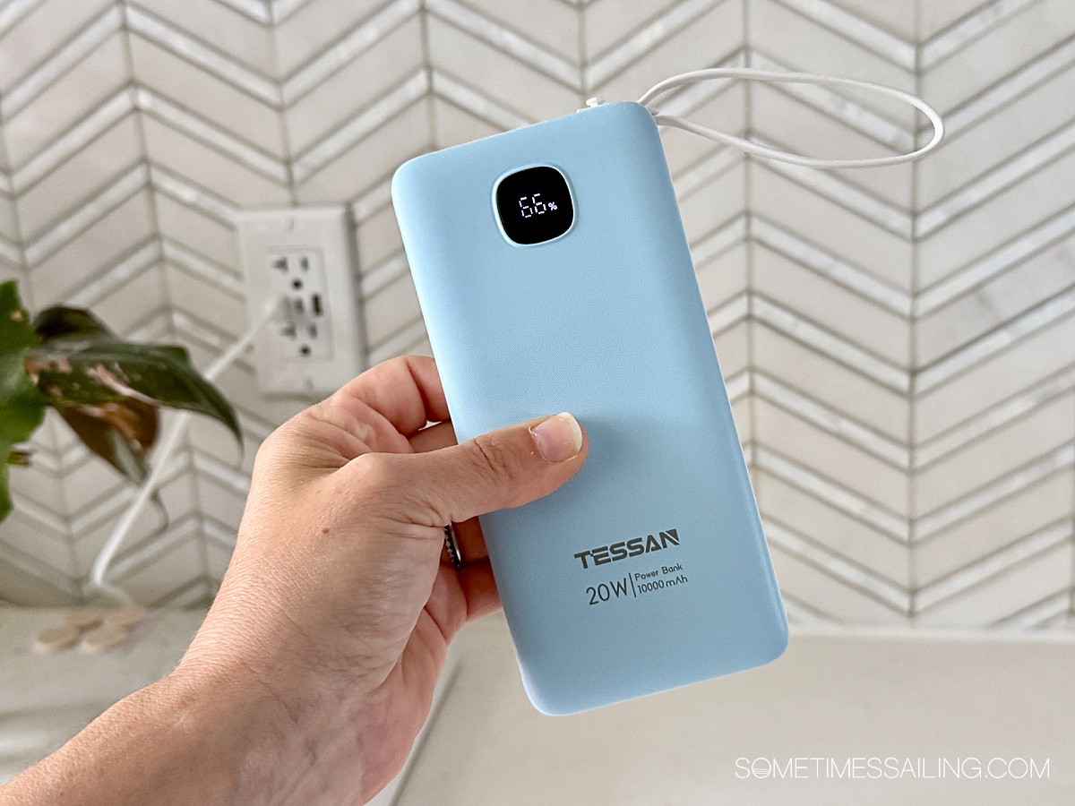 hand holding a blue rectangular battery pack with a small digital display