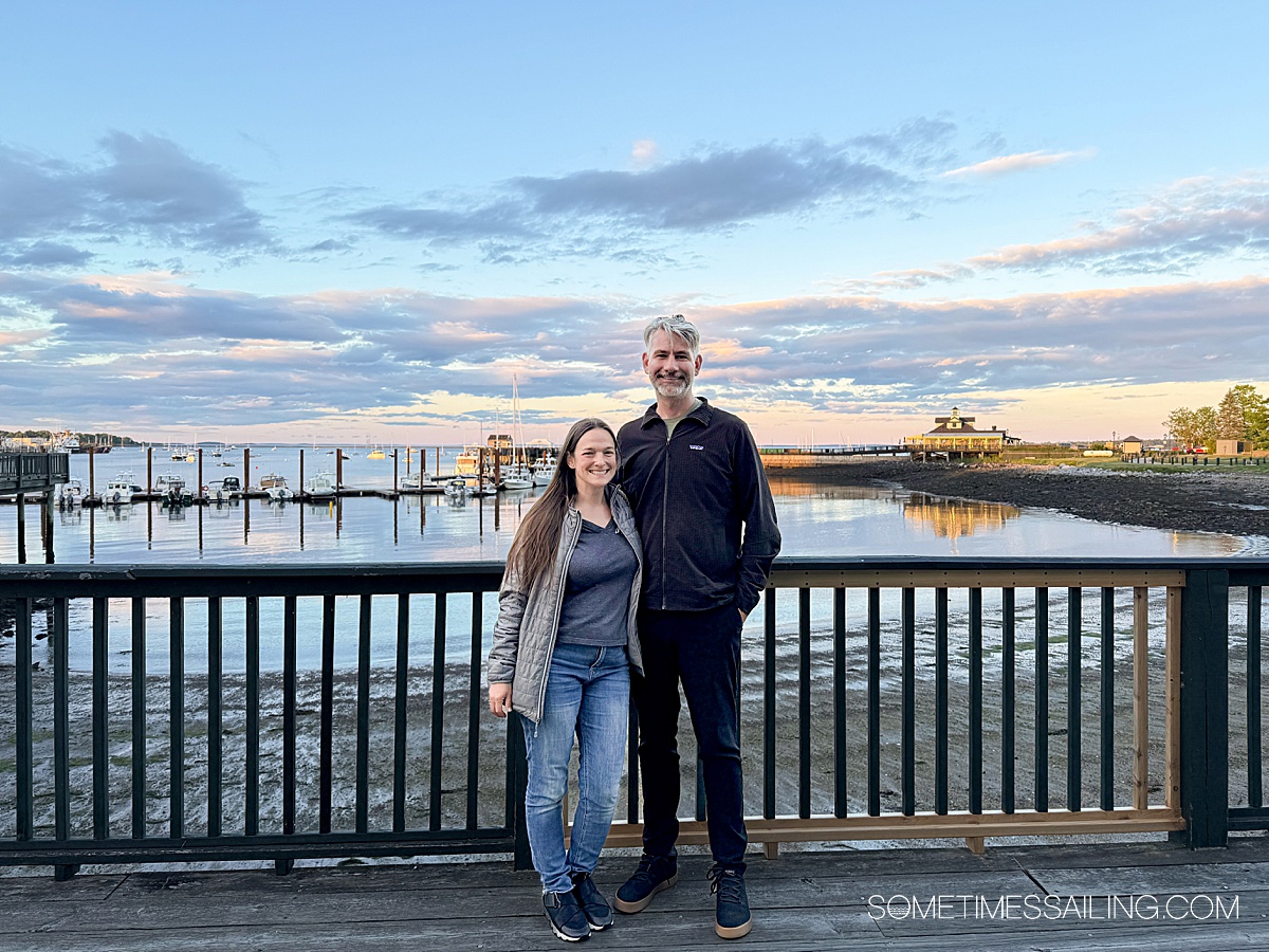 A couple in front of a dusk sky on the waterfront in Rockland, Maine.